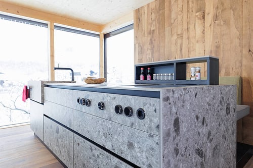 Moderne Küche mit grauer Steininsel und schwarzen Knöpfen